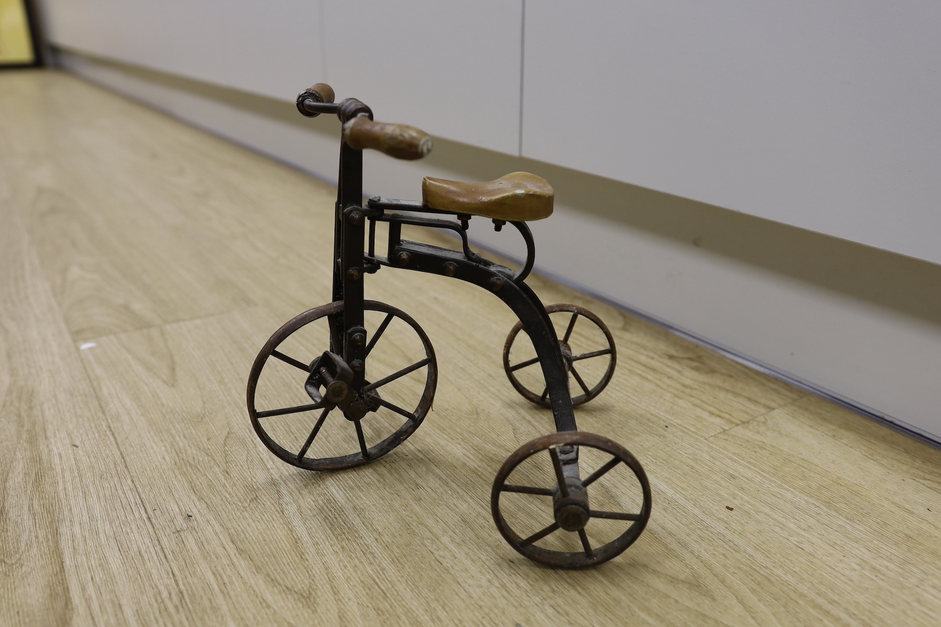 A cast iron toy model of a tricycle, a carved wooden bow, a classical figurative door knocker, a pair of metal cow shoes and two ceramic cistern pulls, bowl 30cm diameter. Condition - fair